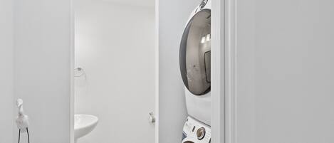A laundry room with a washing machine and a sink.
