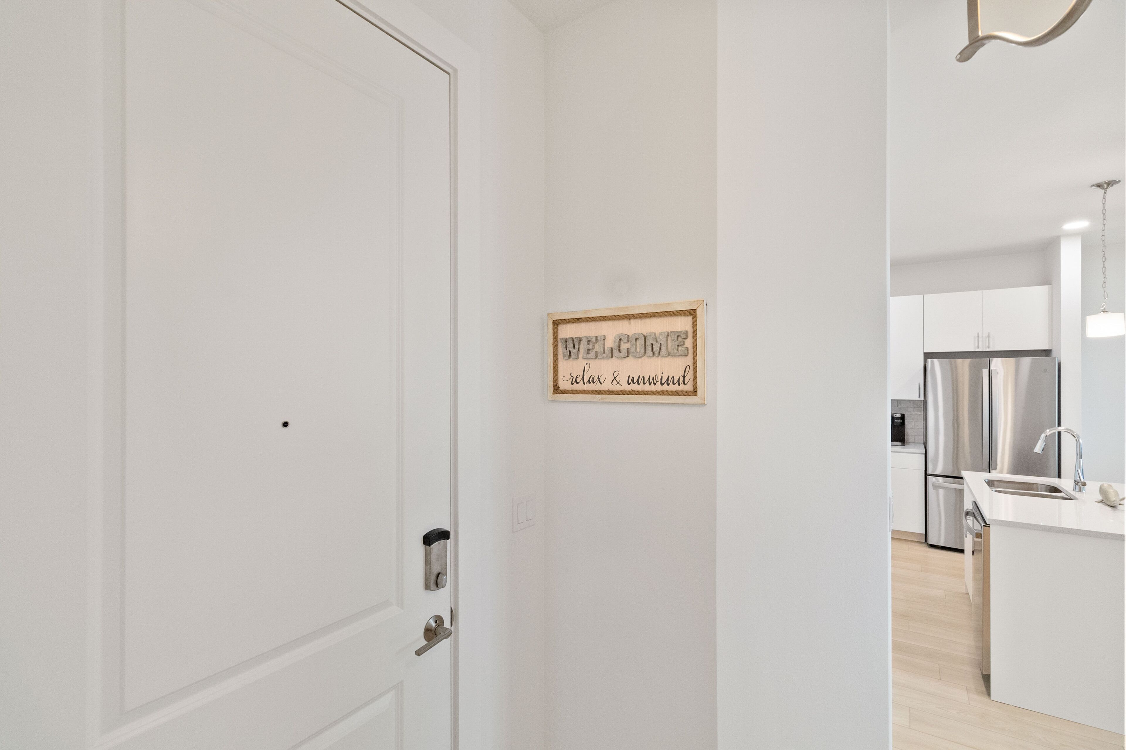 A modern kitchen with stainless steel appliances, a white countertop, and a hanging light fixture.