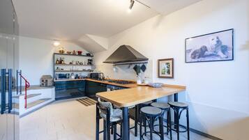A modern kitchen with a central island, bar stools, and a dining table.