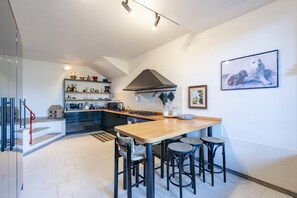 A modern kitchen with a central island, bar stools, and a dining table. - Villa Renetta (San Massimo)