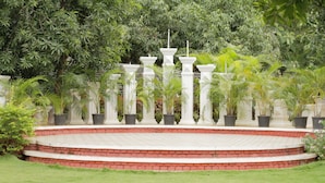 A circular garden with a brick pathway and white pillars. - Reva Resorts & Holiday Homes (Puttur)