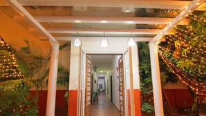 A corridor with a glass ceiling, wooden doors, and string lights. - Reva Resorts & Holiday Homes (Puttur)