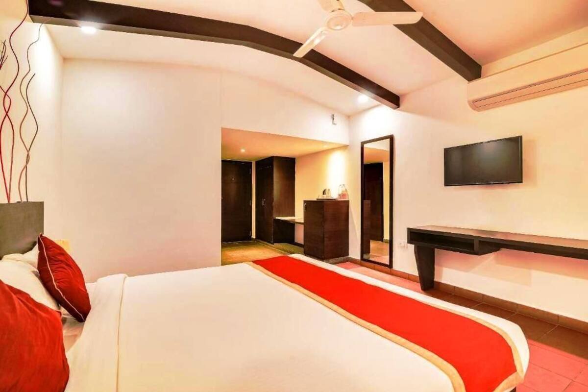 A modern hotel room with a large bed, a TV mounted on the wall, and a desk.