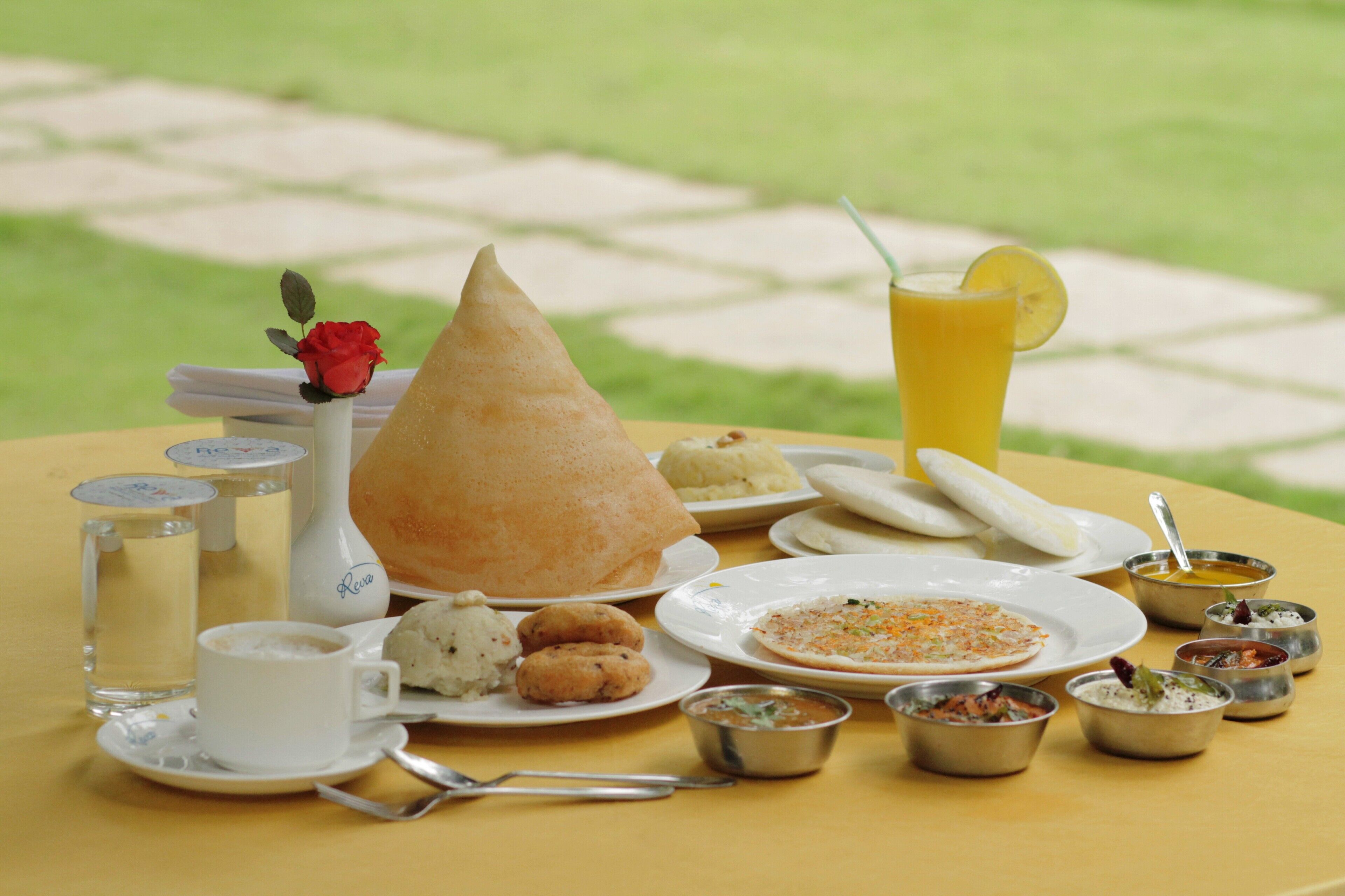 A table set with various dishes, including a cone-shaped item, plates of food, and small bowls of sauces.