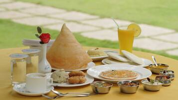 A table set with various dishes, including a cone-shaped item, plates of food, and small bowls of sauces.