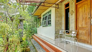 Una casa con porche, una puerta de madera y una ventana con contraventanas verdes.