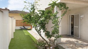 A small backyard with artificial grass, a tree, and a stone patio. - GERKENS: Holiday home with communal pool in l'Escala (L'Escala)