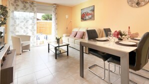 A modern living room with a dining area, featuring a sofa, a coffee table, and a dining table set for four. - GERKENS: Holiday home with communal pool in l'Escala (L'Escala)