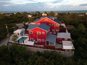 Ein großes rotes Haus mit mehreren Zimmern, einem Pool und Meerblick.