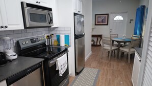 A kitchen with stainless steel appliances, a dining area with a table and chairs, and a patterned rug. - Poolside Tiny House, steps away from the pool! Privacy gate & keyless! (Blue Hills)