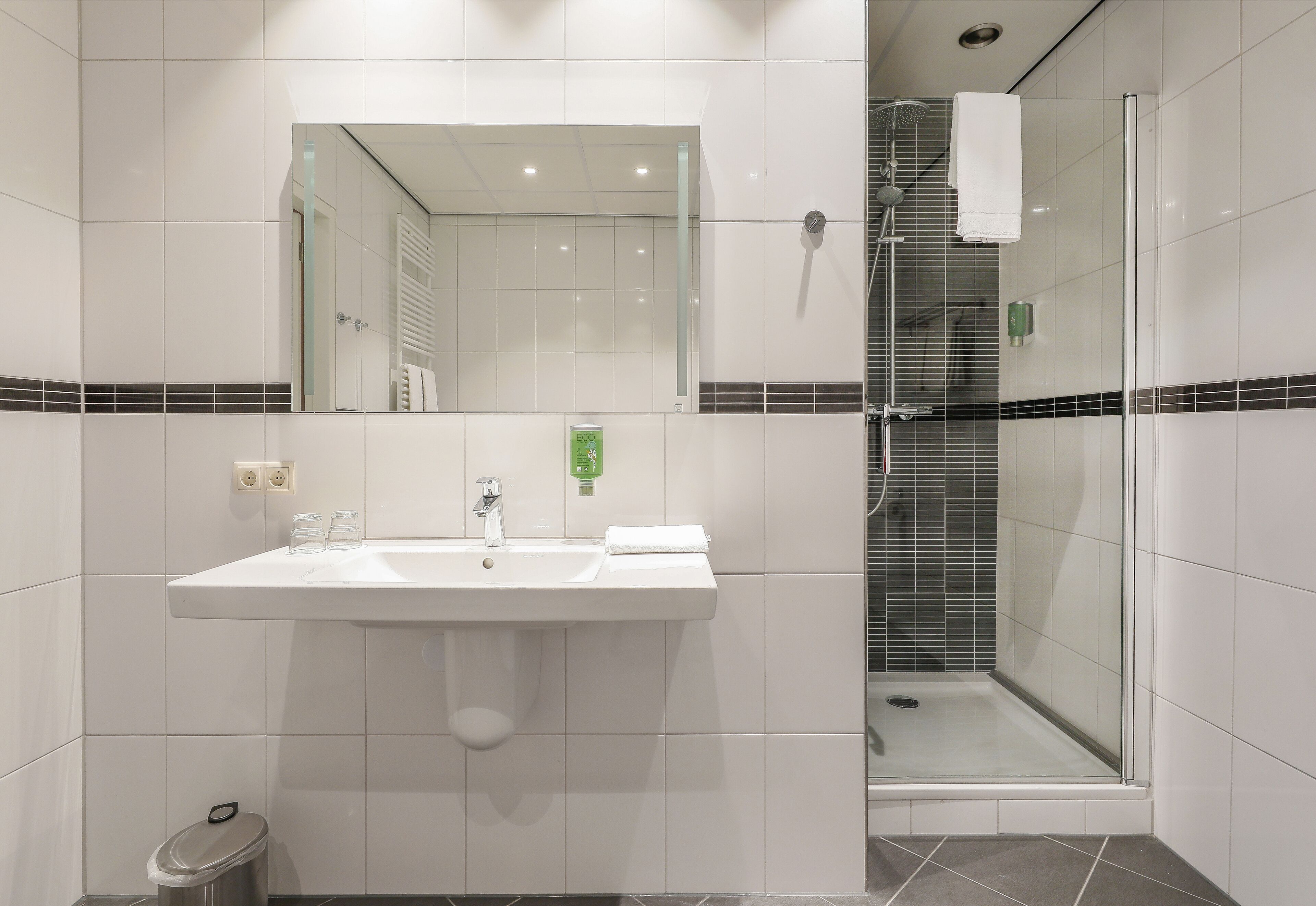 Une salle de bain moderne avec un lavabo, un miroir et une douche à parois de verre.