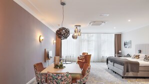 Une chambre d’hôtel moderne dotée d’un coin repas, d’un canapé et d’une grande fenêtre.