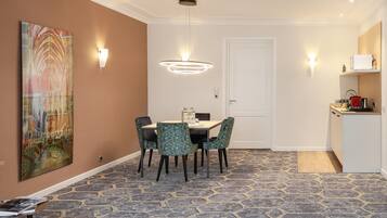 Un comedor con una mesa, sillas, una lámpara en la pared y una puerta al fondo.