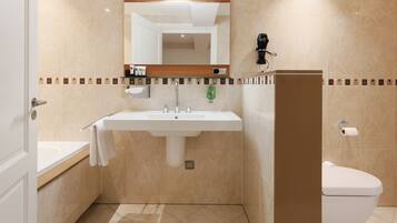 Une salle de bain équipée d’un lavabo, d’un miroir, de toilettes et d’un porte-serviettes.