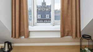 Une pièce avec une fenêtre, un bureau en bois, deux chaises rouges, un contenant en treillis noir et un panneau d’accueil.