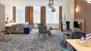 Une chambre d’hôtel comprenant un lit, un canapé, une table à manger, une télévision et une cheminée.