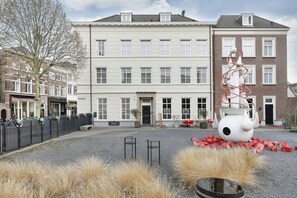 Une cour avec une grande sculpture, un bâtiment doté de nombreuses fenêtres et une clôture.