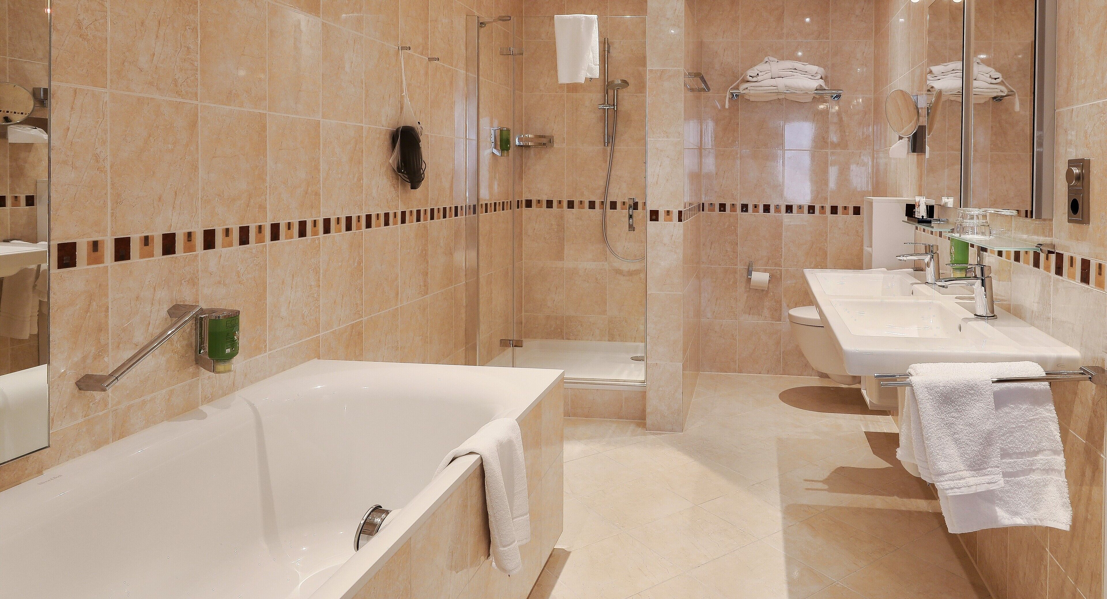 A modern bathroom with a bathtub, shower, and two sinks.