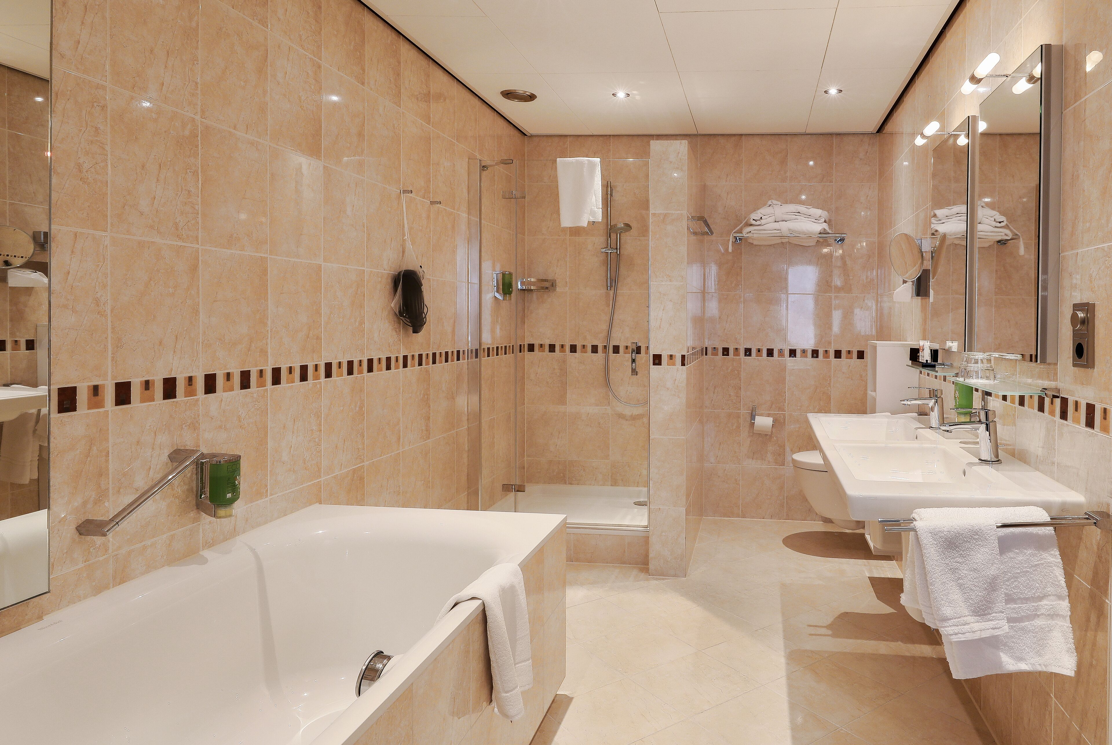 Une salle de bain moderne avec une baignoire, une douche et deux lavabos.
