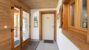 Ein Holzbodenkorridor mit Glastüren zu einem Zimmer, eine Tür mit Herzdeko und ein Fenster mit Holzrahmen.