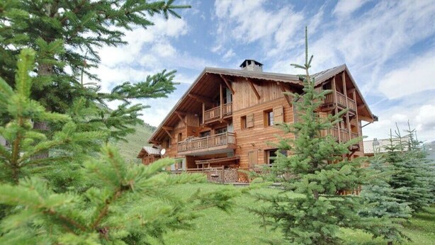 Eine Holzhütte mit Balkon, umgeben von immergrünen Bäumen.