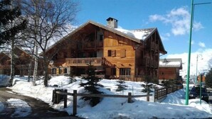 Ein großes Holzhaus mit einem Balkon, umgeben von Schnee und Bäumen.