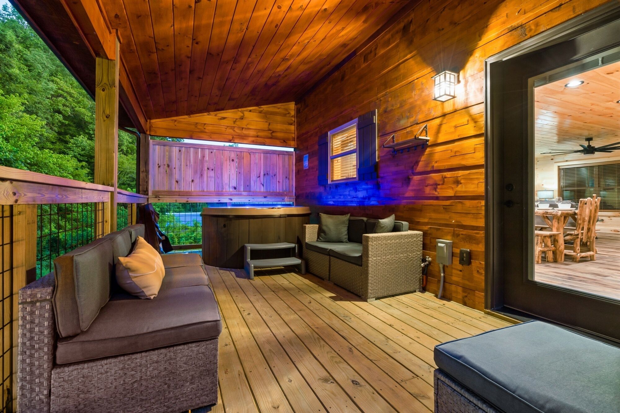 A wooden deck with a sofa, chairs, and a hot tub.