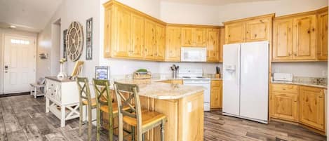 A kitchen with wooden cabinets, a white refrigerator, and a wooden dining table with chairs.