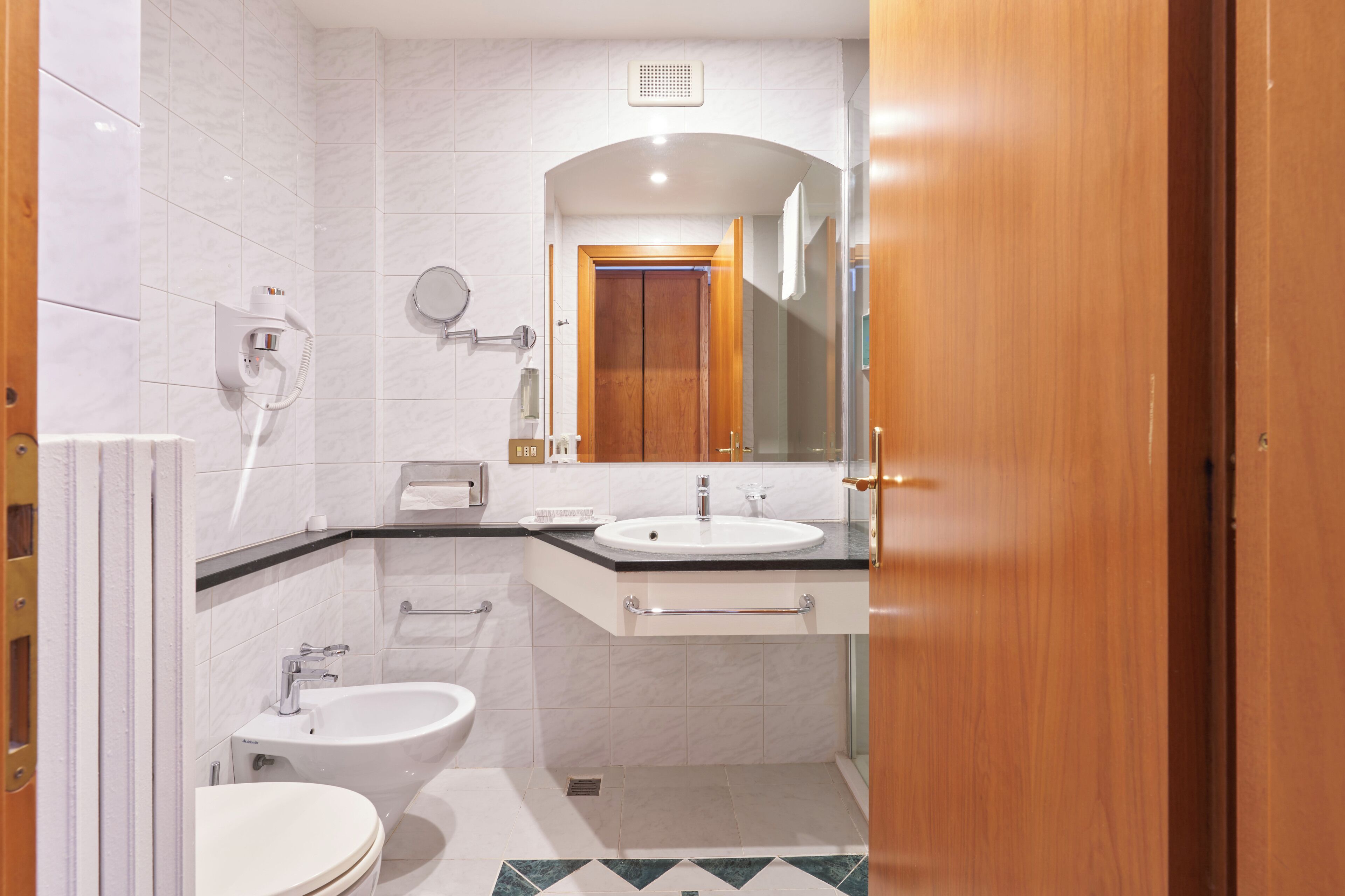 Un baño moderno con inodoro, bidé, lavamanos y espejo.