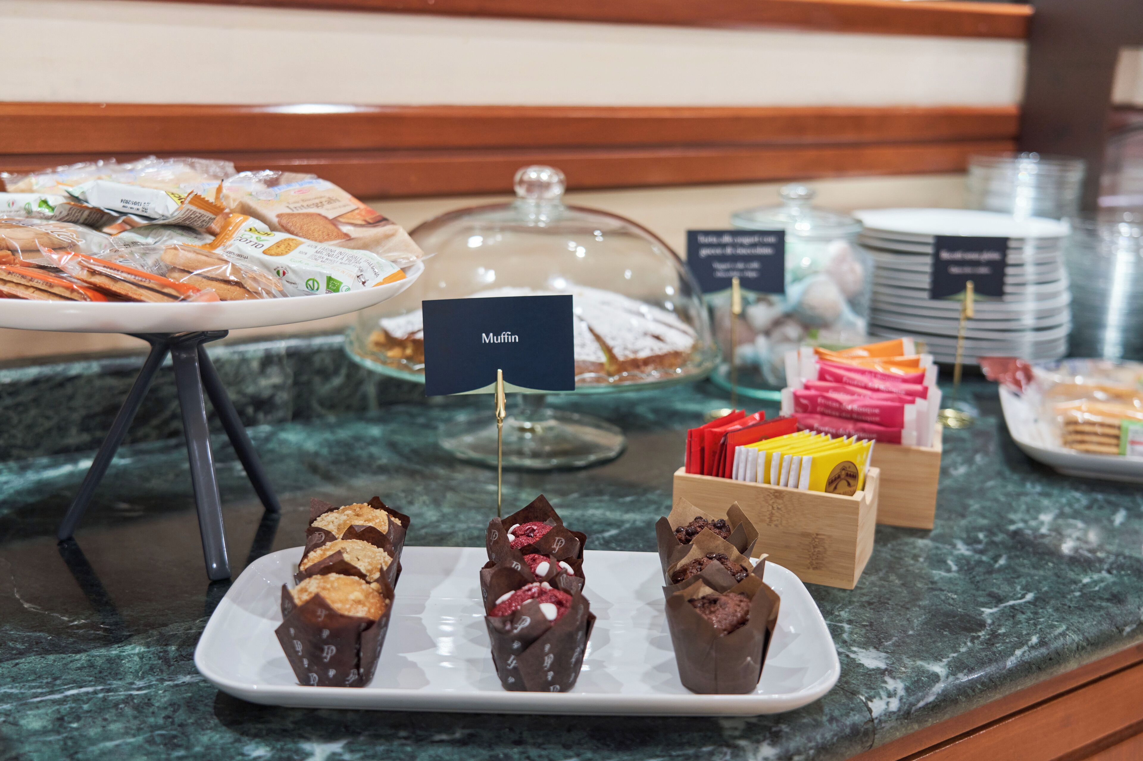 Un bufé con diversos alimentos, incluyendo muffins, pastelería y postres de chocolate.