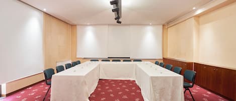A conference room with a long table, chairs, and a projector.