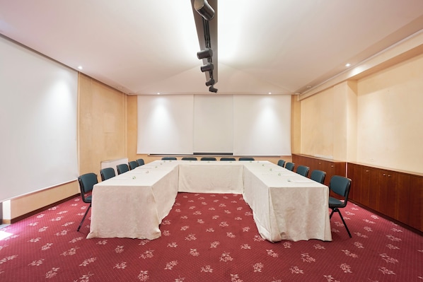 A conference room with a long table, chairs, and a projector.