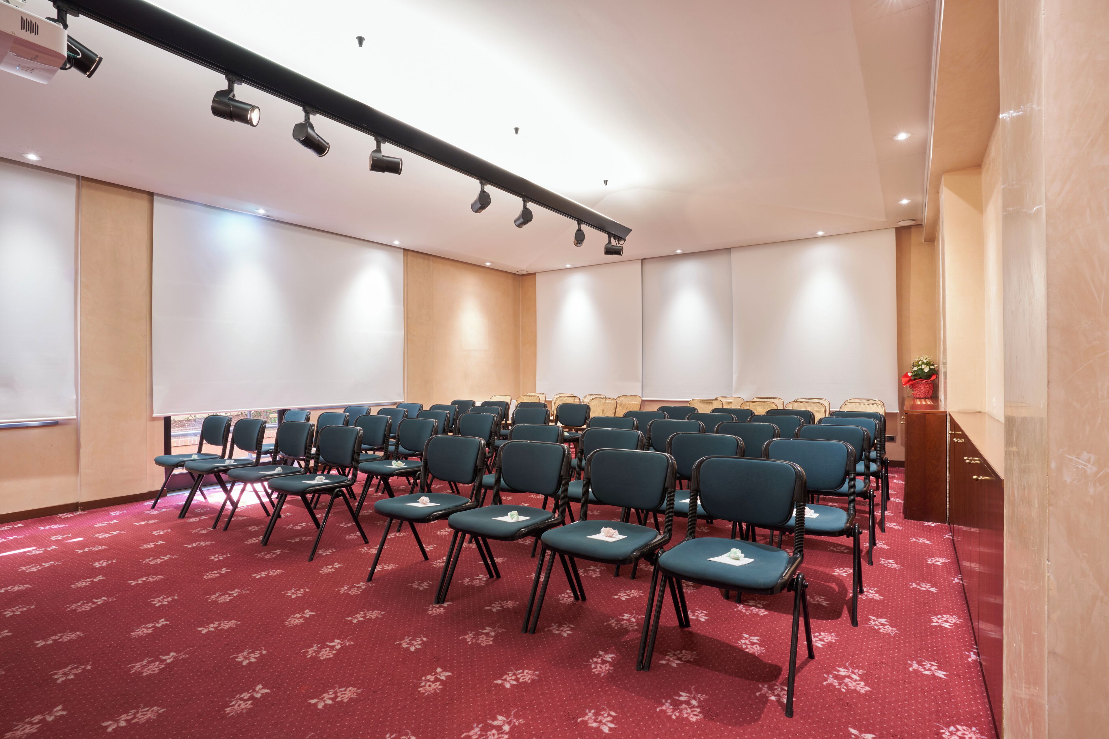 A conference room with rows of chairs, a projector, and a screen.
