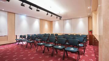 A conference room with rows of chairs, a projector, and a screen.