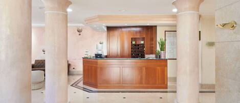 A reception area with a wooden reception desk, a seating area with a sofa, and a potted plant.