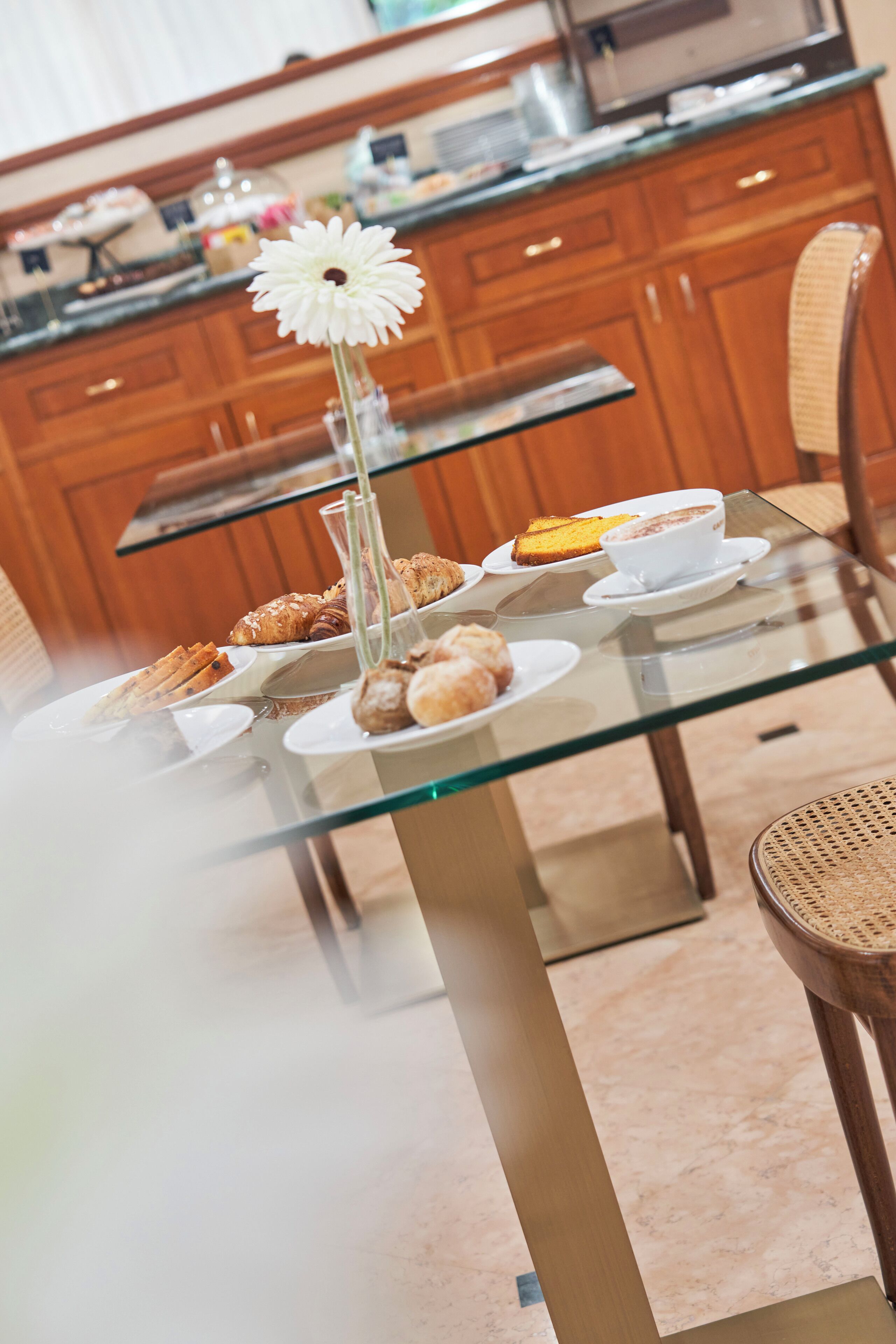 A glass-top table with pastries and a white flower arrangement.