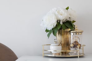 A white vase with white flowers on a gold and white table. - Elite Apartments Letnica Glamour (Gdansk)