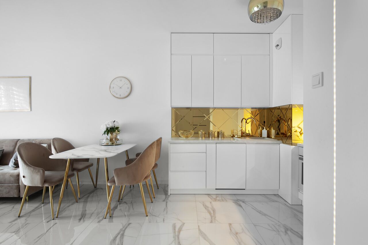 Une cuisine moderne avec des armoires blanches, un comptoir en marbre et des éléments décoratifs dorés.