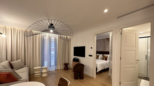 Una camera d'albergo moderna con angolo ristoro, un letto, una TV e un bagno.