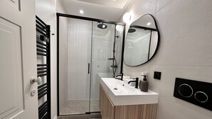 Un bagno moderno con doccia vetro, un mobile vanitario in legno e uno specchio grande.