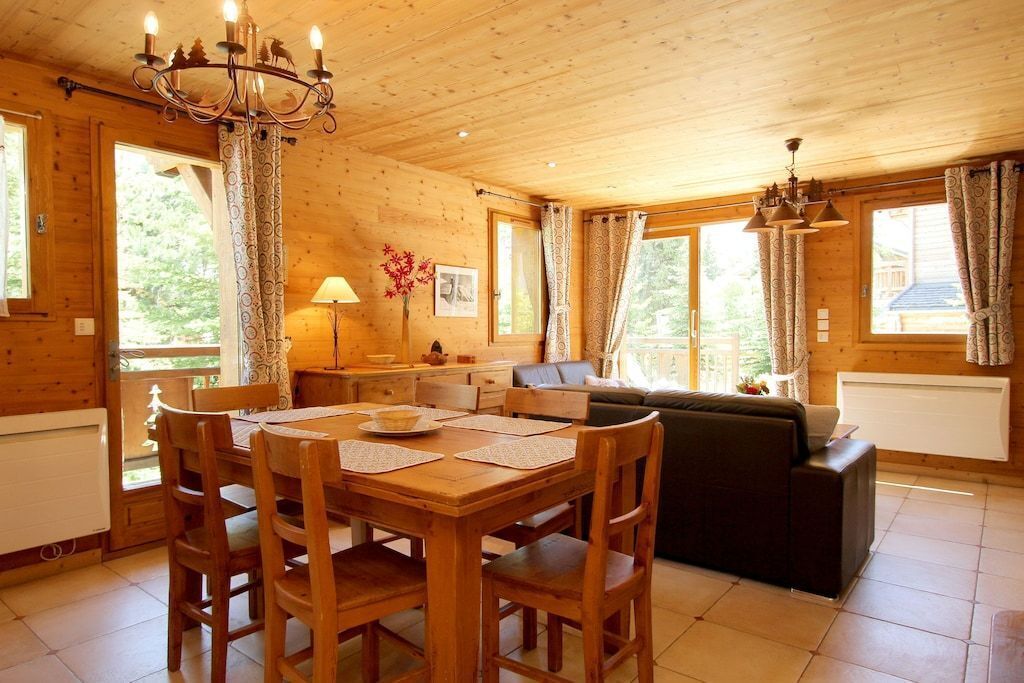 Un intérieur en bois comprenant une table à manger, des chaises, un canapé et un lustre.