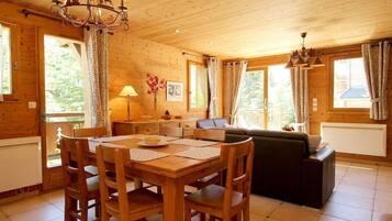 Un intérieur en bois comprenant une table à manger, des chaises, un canapé et un lustre.