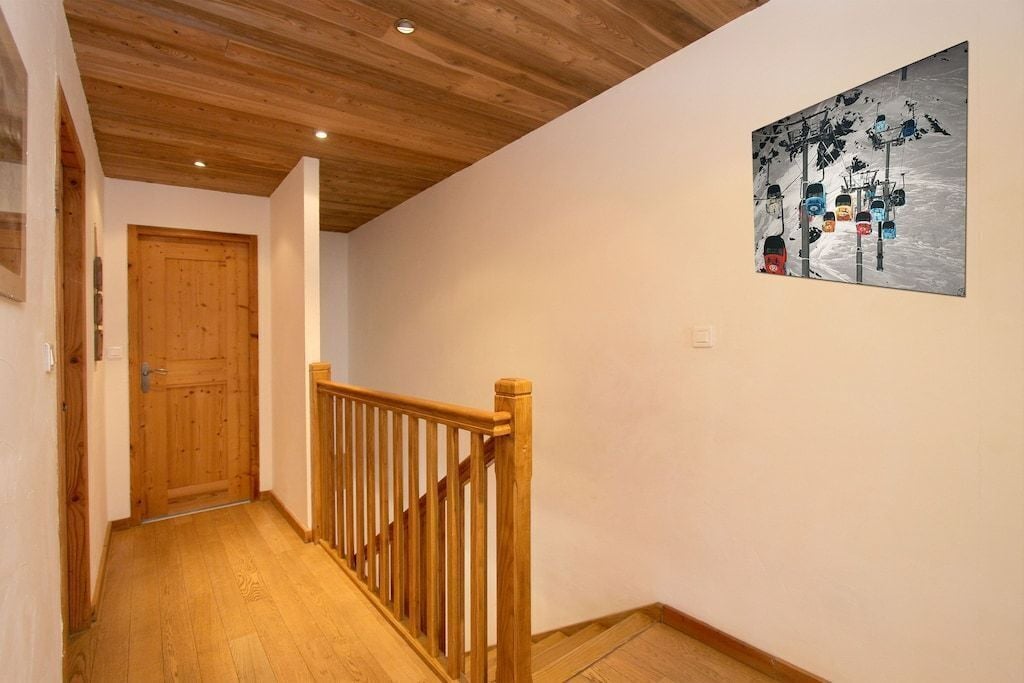 Un escalier en bois, doté d’une rampe, mène à une porte.