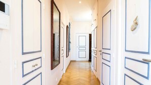 A hallway with white doors and blue trim, wooden flooring, and a mirror on the left wall. - Voltaire - Magnificent 4-bedroom duplex in Triangle d'Or (Bordeaux)