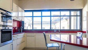 A modern kitchen with a large window, stainless steel appliances, and a red countertop. - Voltaire - Magnificent 4-bedroom duplex in Triangle d'Or (Bordeaux)