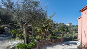 A paved courtyard with stone walls, potted plants, and a tree. - Casa Rosa Tre, Rapallo, 1b/1b with private parking and garden (San Massimo)
