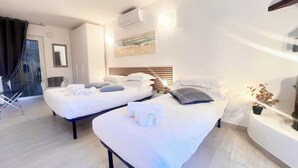 A hotel room with two beds, a small table with a lamp, a potted plant, and a sliding door leading to a balcony. - Casa Rosa Tre, Rapallo, 1b/1b with private parking and garden (San Massimo)