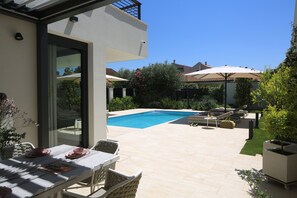 En modern uteplats med pool, sittplatser och en matplats.