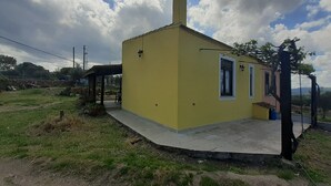 Un pequeño edificio amarillo con chimenea, una ventana y una puerta.