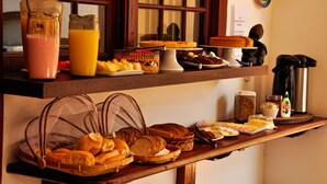 Un bufé de desayuno con panes, pasteles y bebidas diversas.